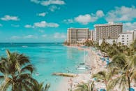 在碧绿的海水和明亮的蓝天下，檀香山威基基海滩的热闹景象充满了活力的游客