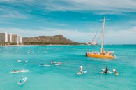 阳光明媚的天空下，冲浪者和黄色双体船俯瞰夏威夷威基基海滩的壮丽鸟瞰图