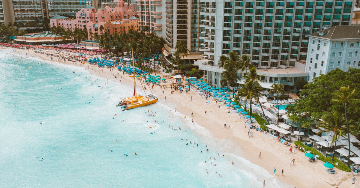 Photo by Jess Loiterton Stunning aerial shot of Waikiki Beach's turquoise waters, sandy shore, and iconic hotels.