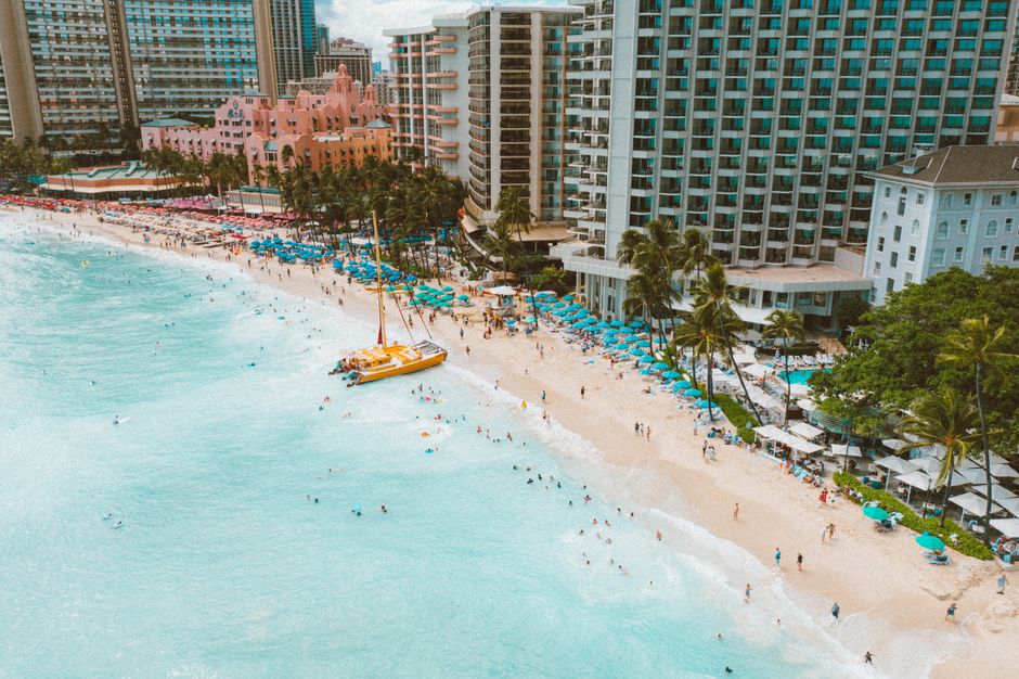 Photo by Jess Loiterton Stunning aerial shot of Waikiki Beach's turquoise waters, sandy shore, and iconic hotels.
