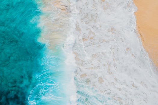 Breathtaking aerial shot of waves crashing on a beach in Honolulu, capturing ocean's vibrant colors.