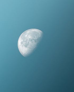 A vivid half moon captured in a serene blue sky, showcasing celestial beauty.