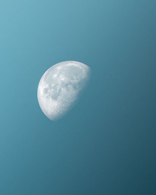 A vivid half moon captured in a serene blue sky, showcasing celestial beauty.