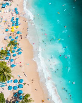 Stunning aerial view of Waikiki Beach in Honolulu with blue umbrellas and turquoise waters.