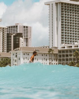 Surfer rides a wave with the striking skyline of Honolulu as the backdrop.