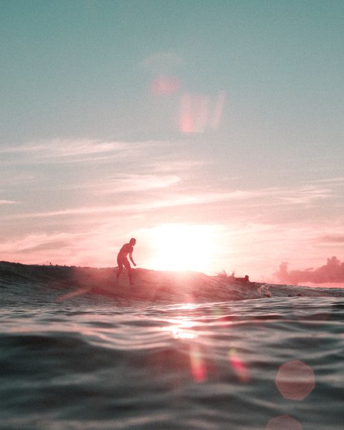 Free A silhouette of a surfer catching a wave at sunset in Honolulu, Hawaii, creating a serene beach atmosphere. Stock Photo