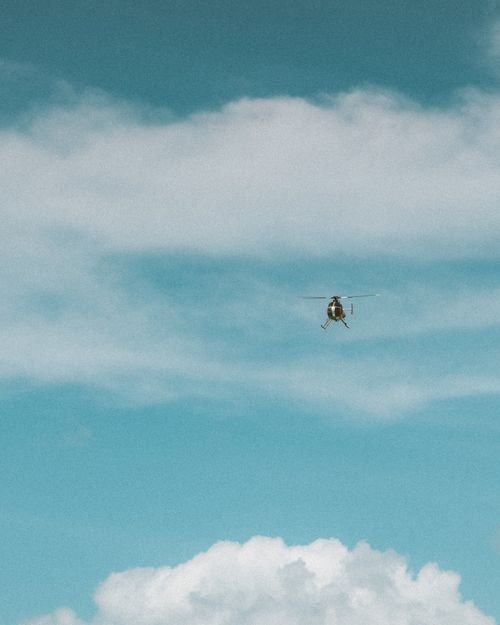 Free A helicopter flying high against a backdrop of blue sky and white clouds. Stock Photo