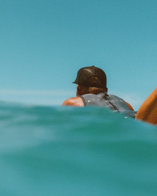 Man in Black Cap Lying on Blue Water