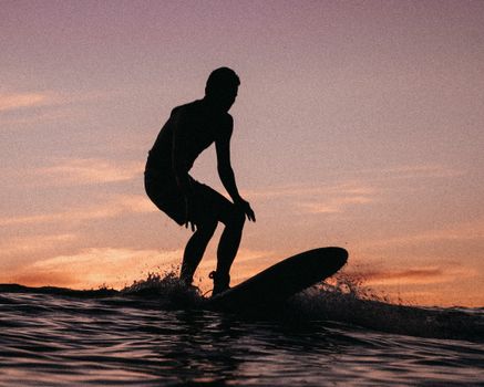 迷人的冲浪者剪影在夏威夷日落中乘风破浪