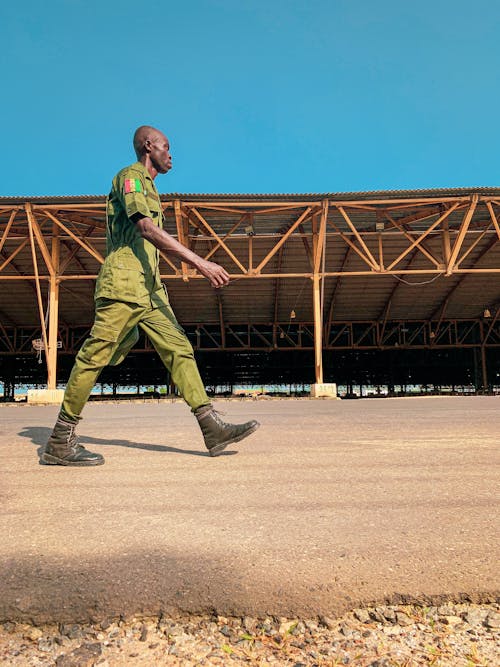 Free Man in Green Uniform Walking on Brown Sand Stock Photo