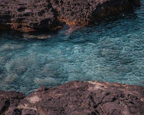 Free Clear turquoise waters meet rugged volcanic rocks in Hawaii's stunning coastline. Stock Photo