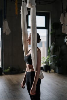 A young woman practicing aerial yoga in a serene indoor studio.
