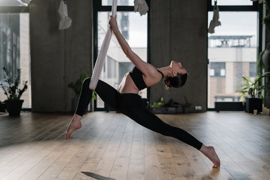 A woman practicing aerial yoga indoors, showcasing flexibility and balance in a modern yoga studio.