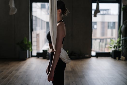 A woman performing aerial yoga, enhancing fitness and well-being indoors.