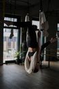 一名女子在室内工作室里，正用吊床织物练习空中瑜伽，摆出具有挑战性的姿势
