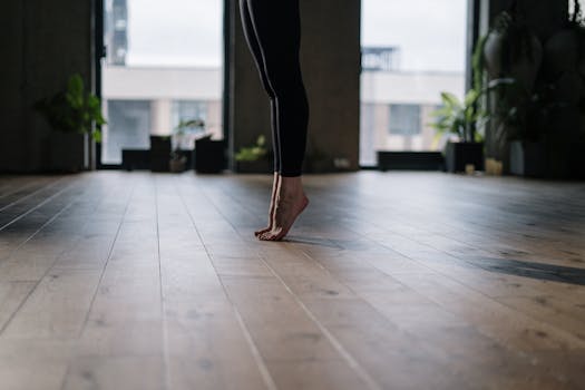 A person practicing a gentle yoga pose indoors, focusing on balance and wellness.