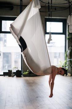 A woman practicing aerial yoga in a modern studio, promoting health and wellness.