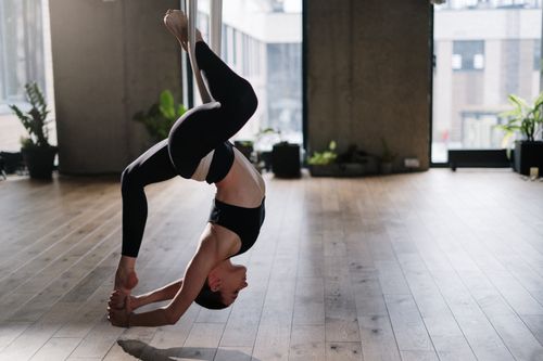 Free A woman performing an aerial yoga pose in a modern studio, showcasing balance and flexibility. Stock Photo