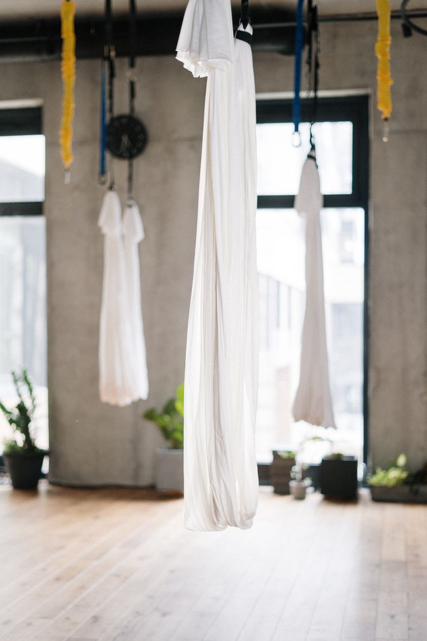 Bright yoga studio with aerial silks and plants, perfect for fitness and wellness.