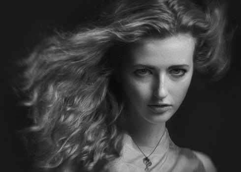 Elegant grayscale portrait of a woman captured in a studio setting with dynamic hair movement.