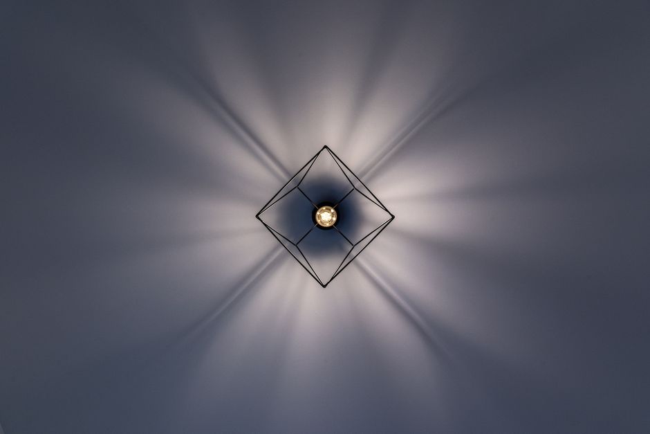 A minimalist geometric ceiling light with striking light and shadow patterns. Our top tips for a grand ceiling finish