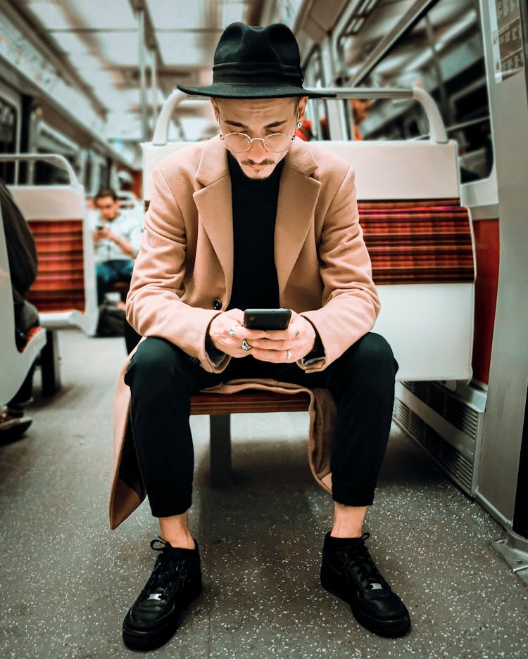 Elegant Man In Hat And Eyeglasses Using Smartphone In Modern Train