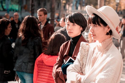 两名时尚女士在熙熙攘攘的城市人群中，享受着阳光明媚的一天
