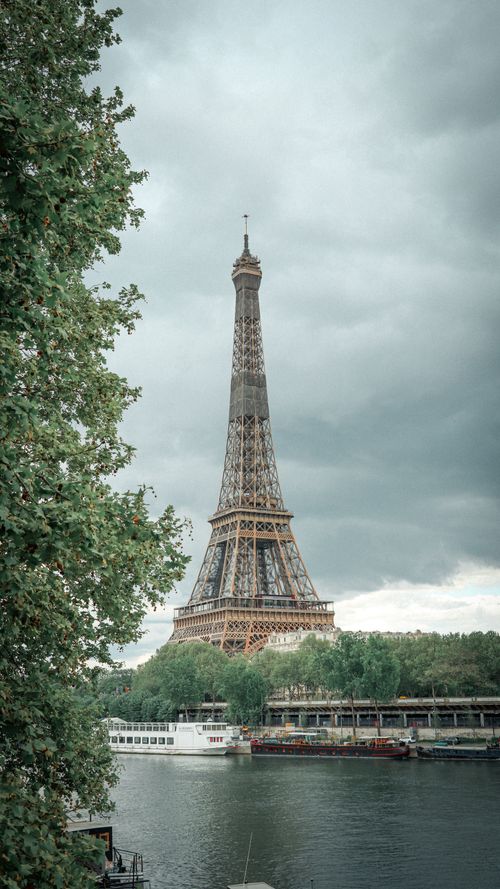 Free From below picturesque scenery of historical Eiffel Tower on shore of Seine river against cloudy sky Stock Photo