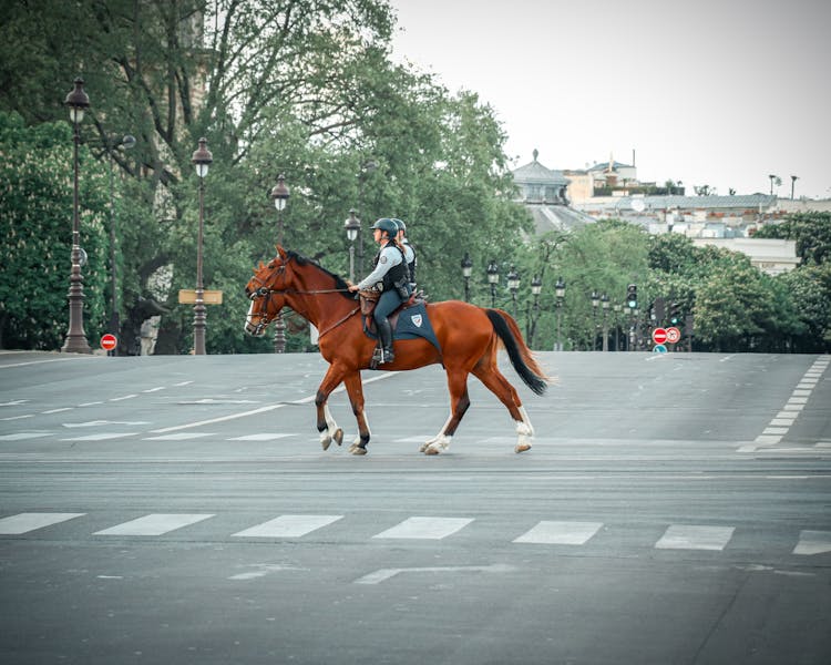 Anonymous People Crossing Street On Horses