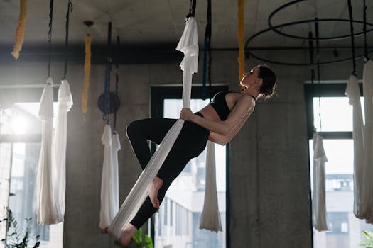 A woman performing aerial yoga gracefully in a modern studio.