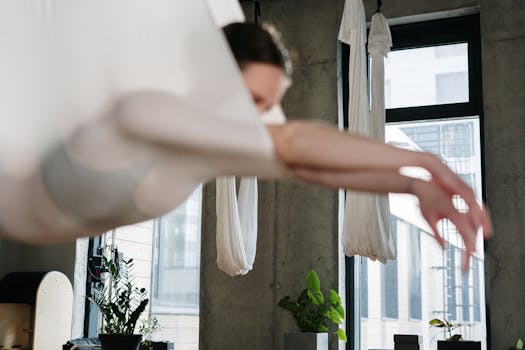 A woman practicing aerial yoga indoors, suspended gracefully in a modern studio.
