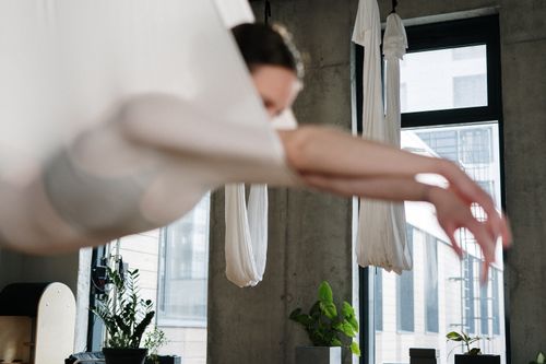 Free A woman practicing aerial yoga indoors, suspended gracefully in a modern studio. Stock Photo