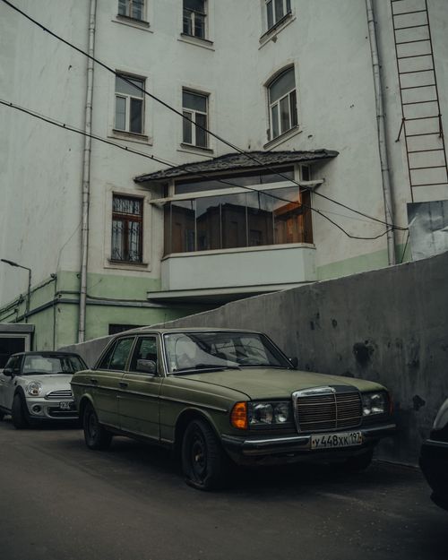 Free Low angle of old fashioned car parked on asphalt street near simple shabby building in city outskirts Stock Photo