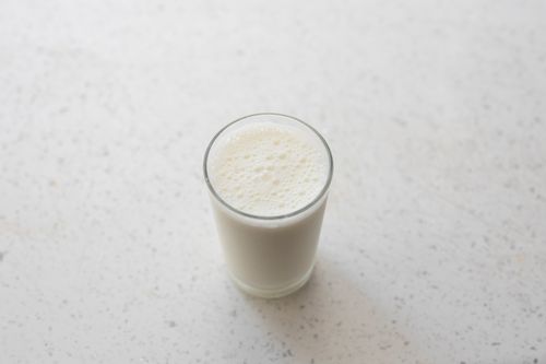 Free A top-down view of a foamy glass of milk on a white marble surface. Perfect for a healthy lifestyle concept. Stock Photo