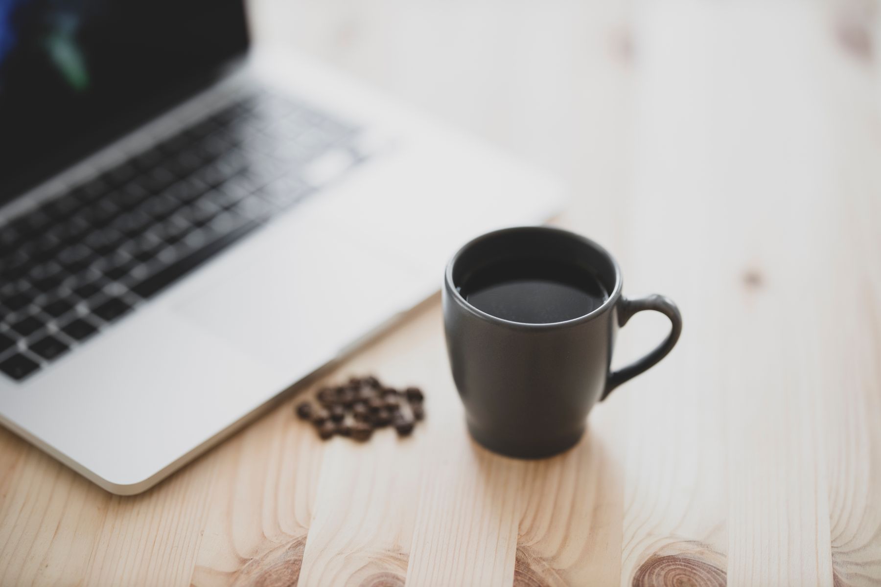 A laptop open on a wooden cafe table beside a cup of Marcala coffee