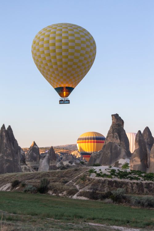 Free Flying green hot air balloon above ground with peaky rocks during festival in nature Stock Photo
