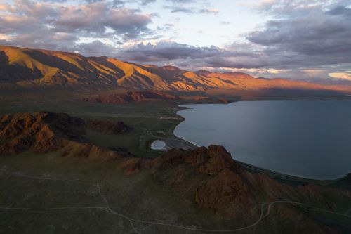 Free Aerial view of small calm lake located amidst mountain range against dramatic cloudy sky during sunset Stock Photo