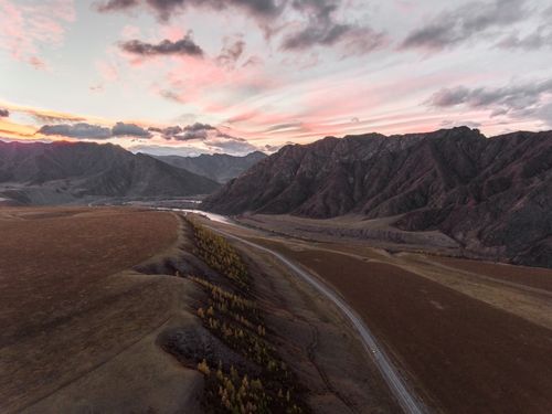 Free Drone view of narrow road between desert mountain slopes and valleys during amazing sundown Stock Photo