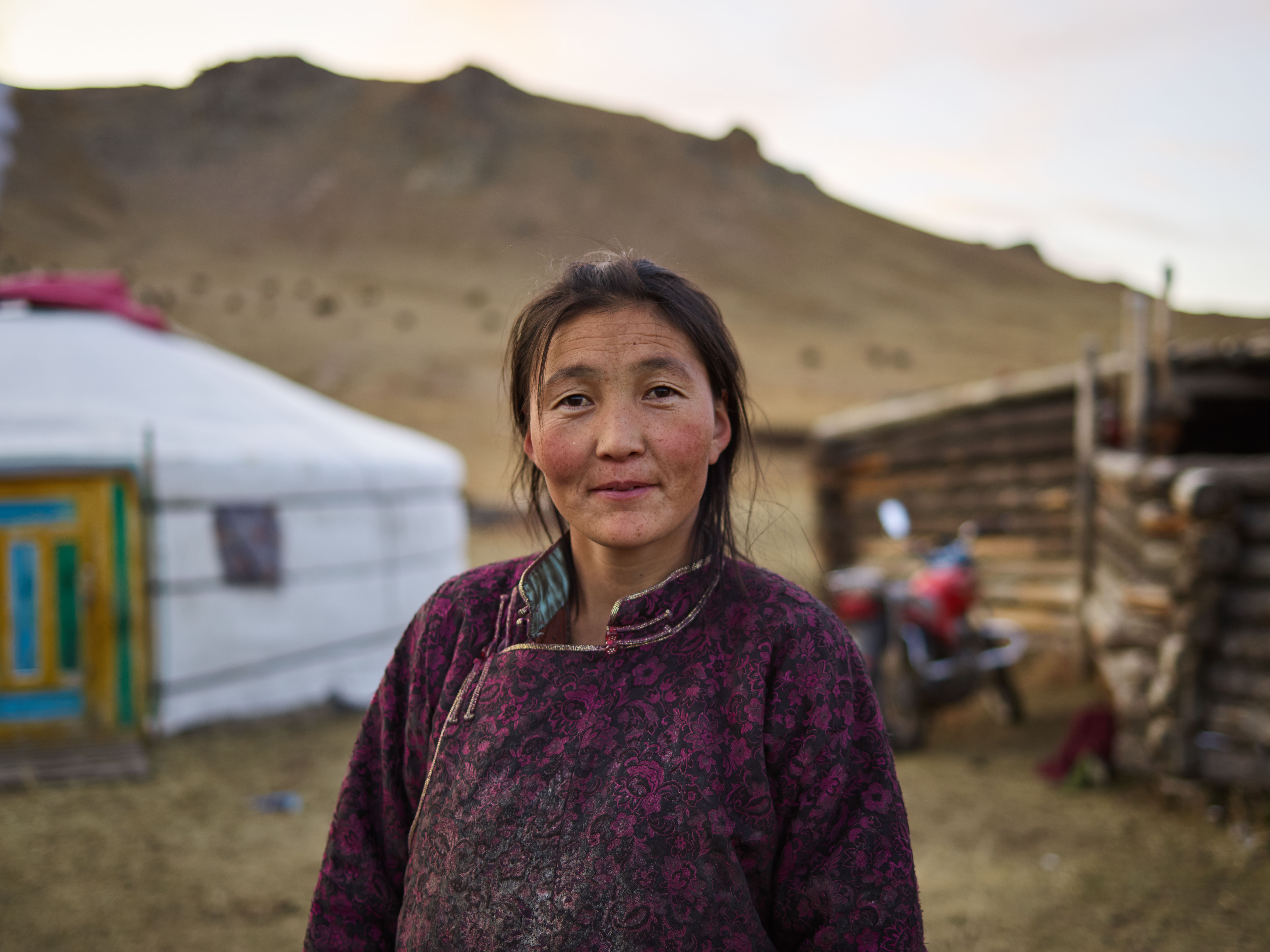 Mongolian woman in traditional national dress standing in front of a ger on the steppe