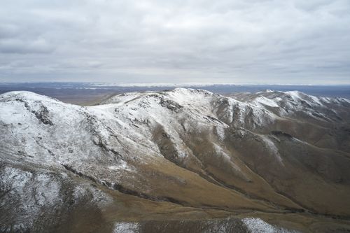 Free Aerial view of snowy peaks of picturesque mountain ridge against cloudy sky in winter Stock Photo