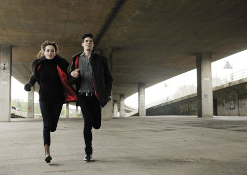 Man and Woman Running Under Bridge