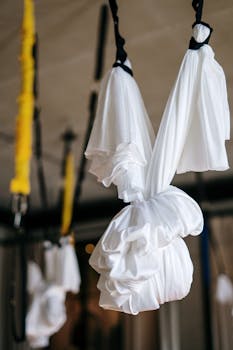 Close-up of white aerial yoga fabrics suspended indoors, ideal for fitness and wellness concepts.