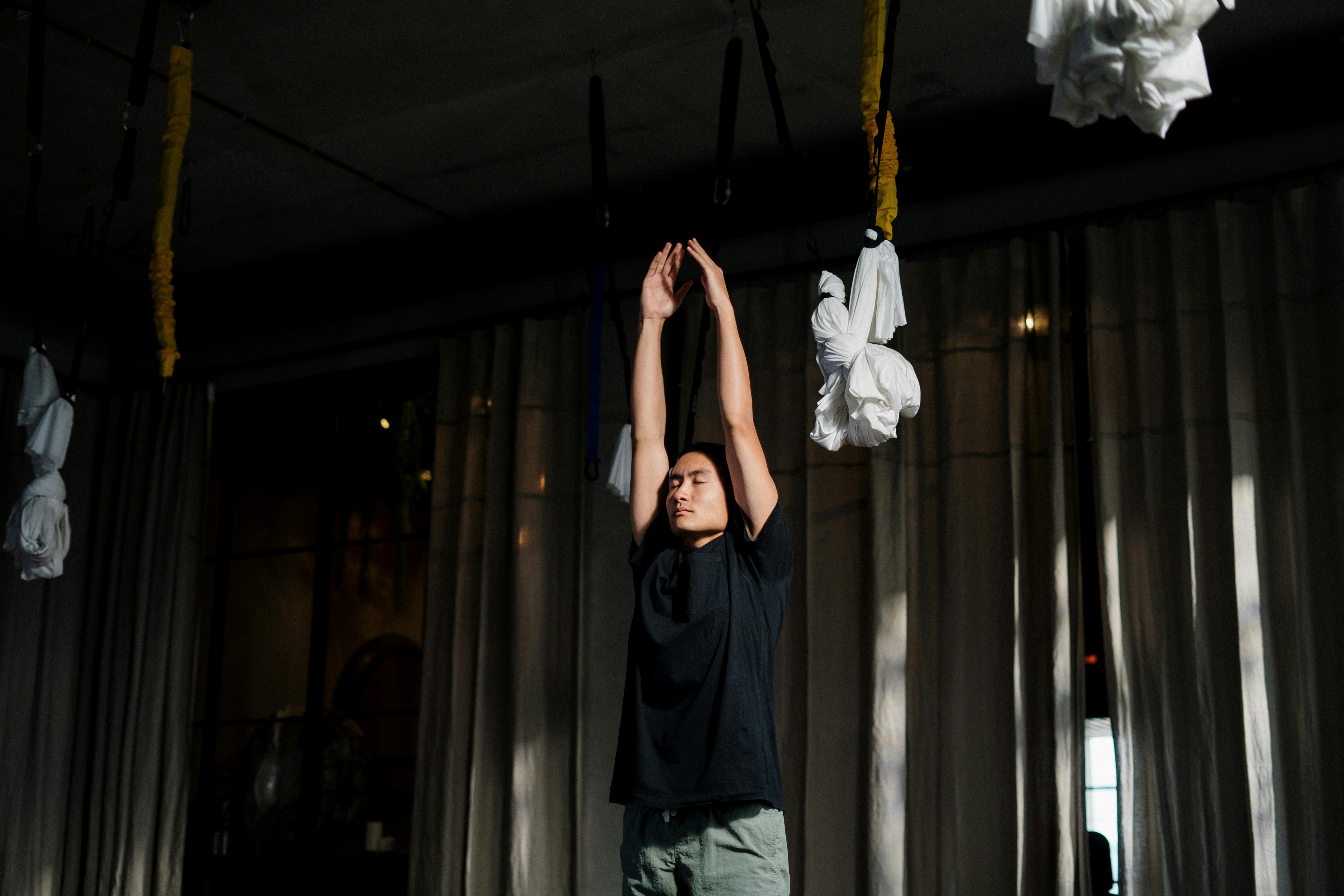 man in black crew neck t shirt and blue denim jeans standing and raising his hands