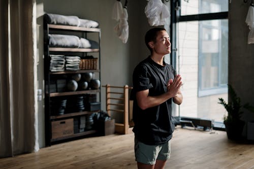 Man in Black Crew Neck T-shirt and Blue Denim Shorts Standing Near White Plastic Bags