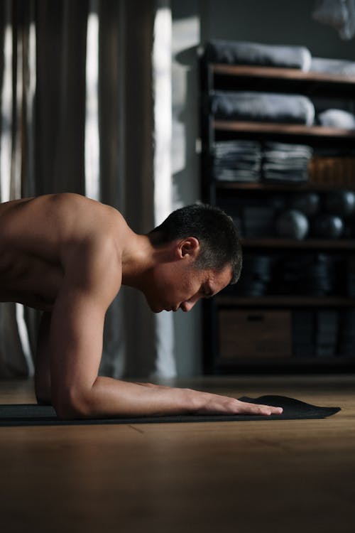 Topless Man Sitting on Brown Wooden Table