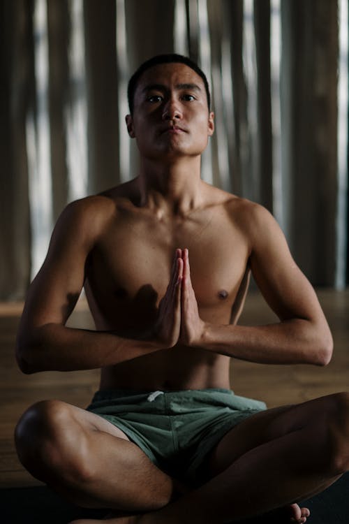 Topless Man in Green Shorts Sitting on Brown Couch