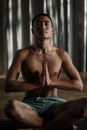 一个光着膀子的男人在宁静的室内工作室练习瑜伽，以促进健康和正念