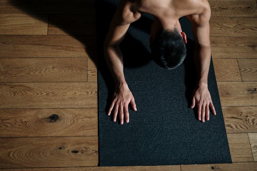 Adult male performing yoga on a mat, emphasizing fitness and wellness.