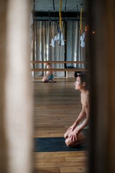 Asian man practicing yoga in a serene studio setting, focusing on wellness.