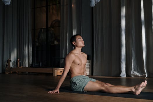 Shirtless man engaged in a yoga session, promoting mindfulness and wellbeing.